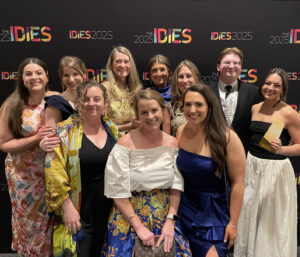 Designers in front of backdrop with awards